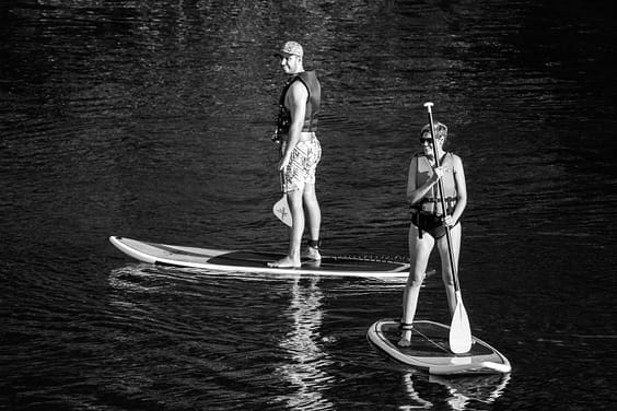 pexels-photo-20876114-20876114 Two people paddleboarding on a lake in Ribeirão Claro, Brazil, in a black and white photograph.