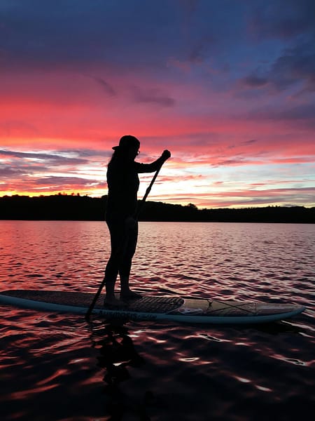 pexels-photo-1751550-1751550 Silhouette of a person paddleboarding on a lake during a vibrant sunset.